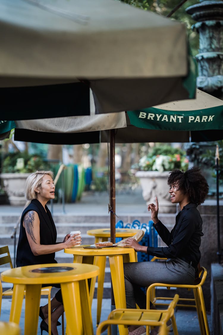 Women Talking By Yellow Cafe Table