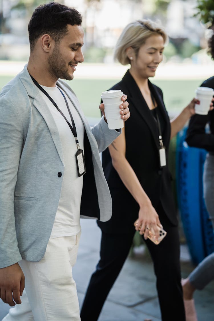 Man And Woman In Elegant Clothing Wearing Identification Badges Walking Holding Disposable Coffee Cups