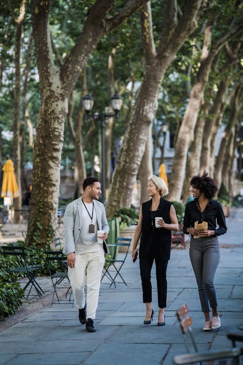 Man and Women in Formal Clothing Wearing Identification Badges Walking with Cups of Coffee in Their Hands 