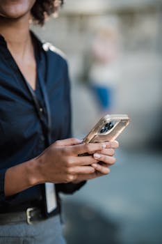 Close-up of a black woman using a smartphone outdoors, focusing on technology and lifestyle.