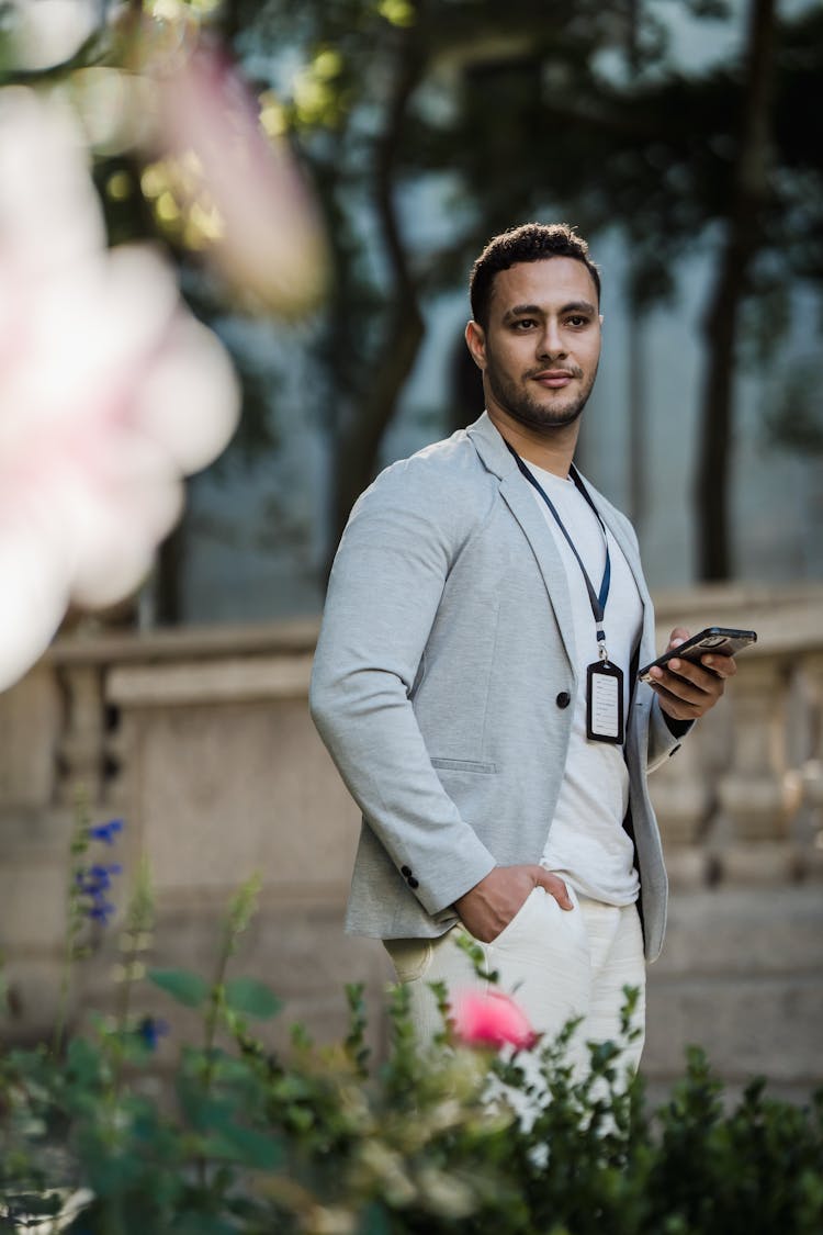 Man Walking Through Park With Phone In Hand