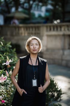 Professional woman in an outdoor park setting with flowers in focus.