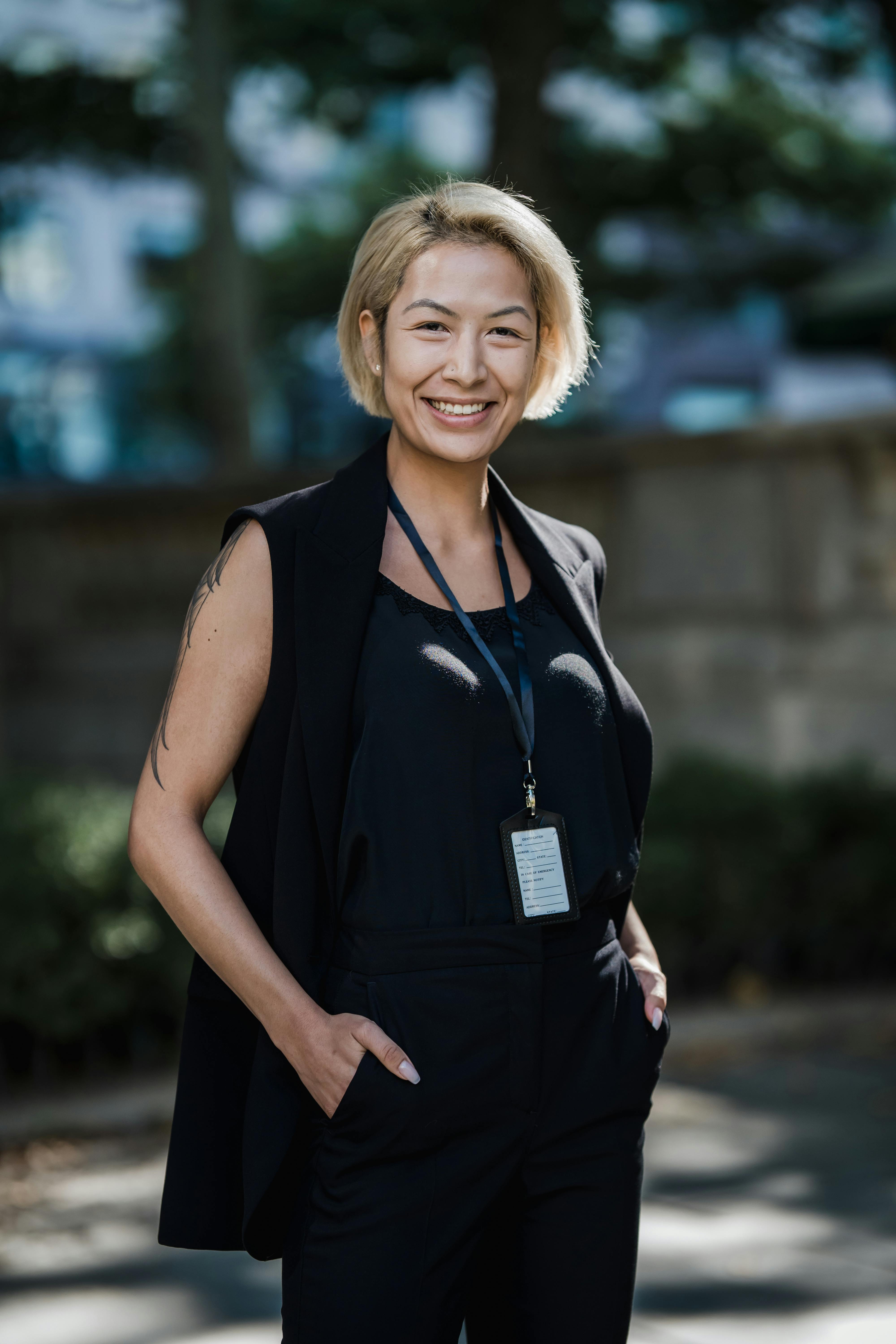 Confident professional woman smiling in an outdoor setting, wearing formal attire.