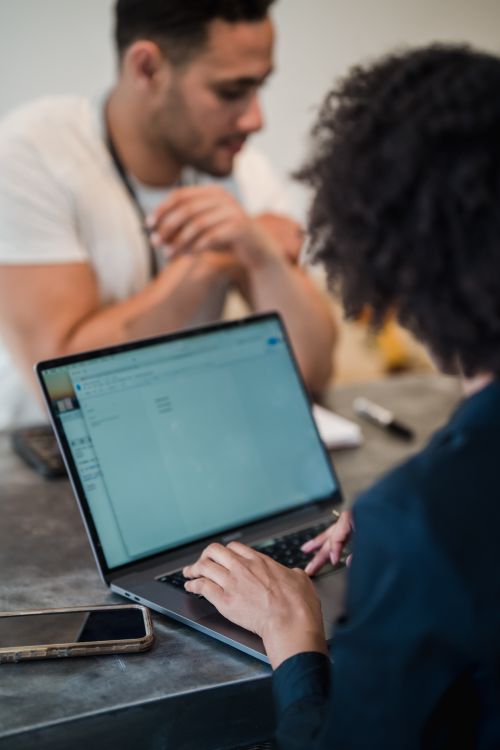 Free Two adults in an office setting collaborating on a project using a laptop. Perfect for business and teamwork concepts. Stock Photo