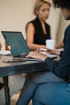 Professional woman typing on a laptop in a modern office environment.