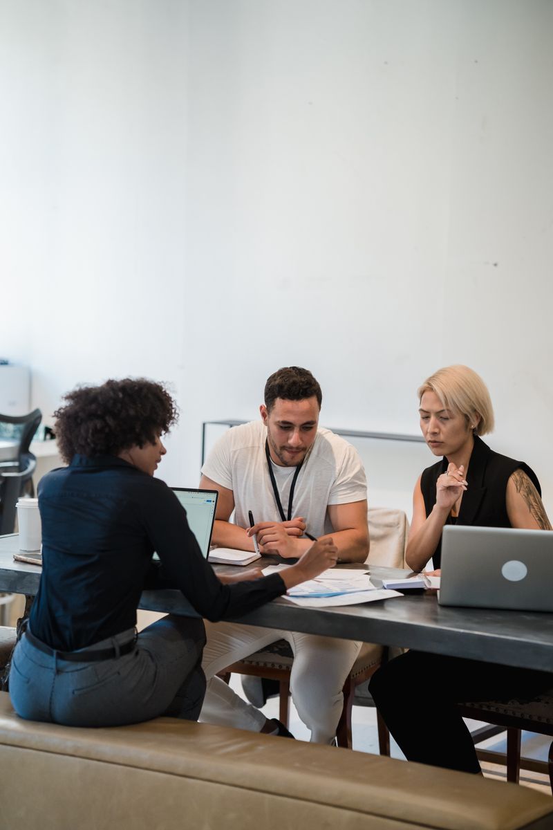 Diverse team focused on collaboration at office table with laptops and documents. Ideal for business themes.