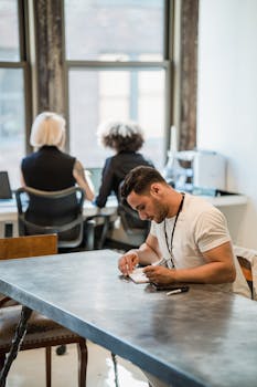 Team in modern office working at desks, collaborating on projects with natural light.