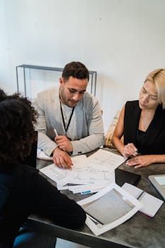 Diverse team engaged in collaboration, reviewing documents at an office desk.
