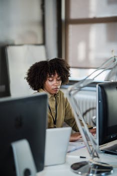 Woman concentrating on her work at a computer desk in a modern office environment.