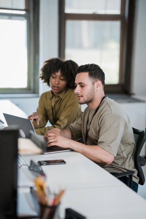 Free Two colleagues working together on a laptop in a modern office setting. Stock Photo