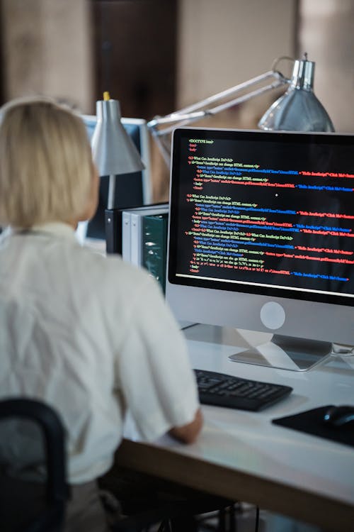 Vertical Shot of a Woman in an Office Looking at a Computer Screen with Multicoloured Script