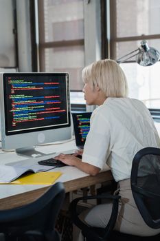 Woman engaged in software programming in a contemporary office setting with multiple screens.
