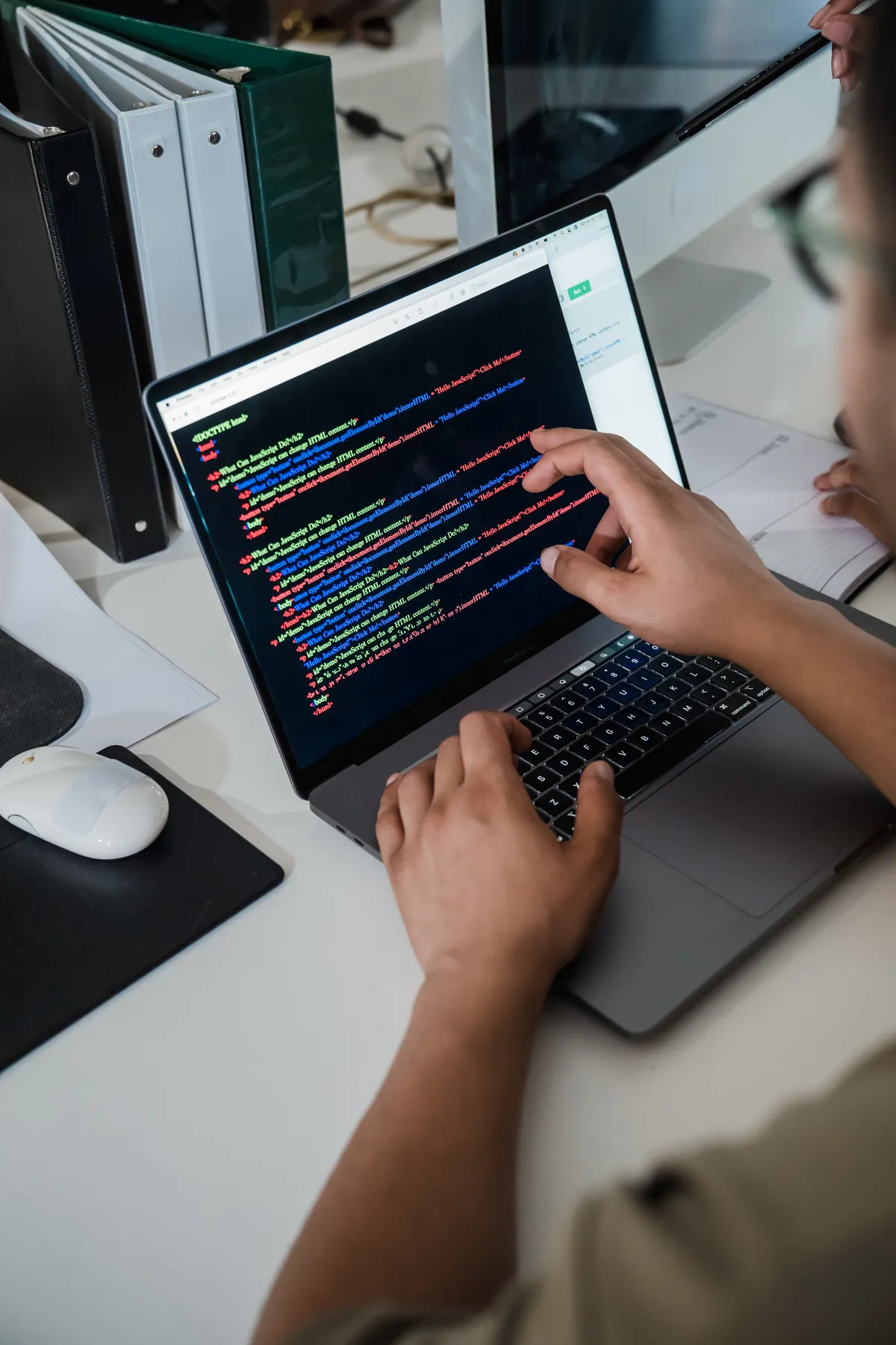 A person pointing at lines of code on a laptop screen while debugging a program.