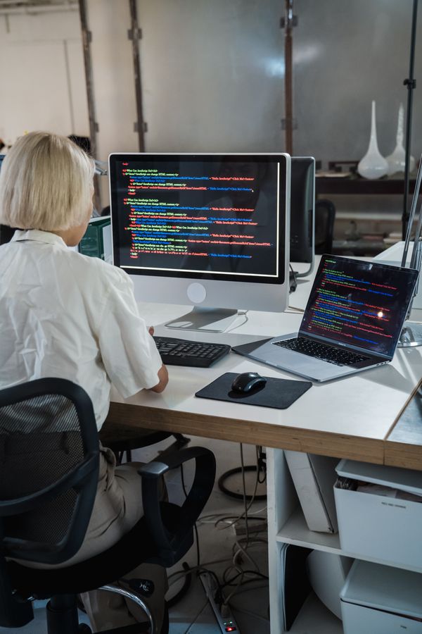 Developer closely examining code across two monitors
