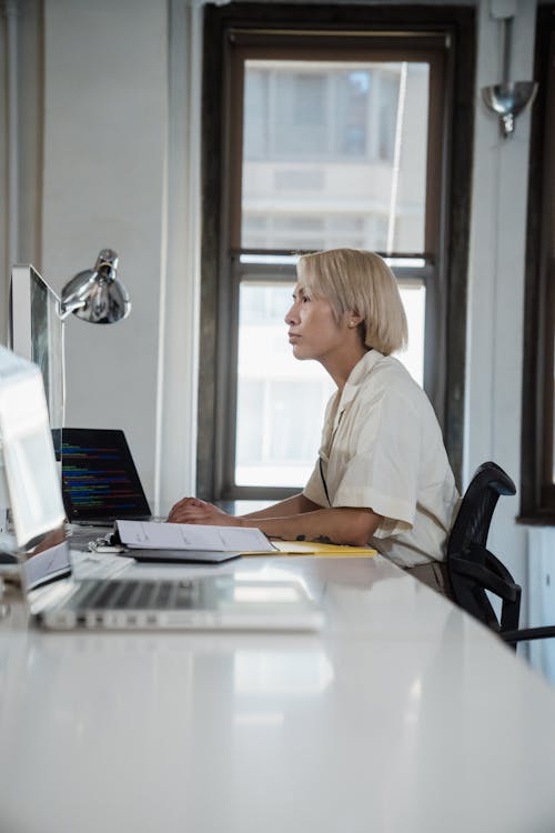 Blonde Woman Sitting at Desk in Office