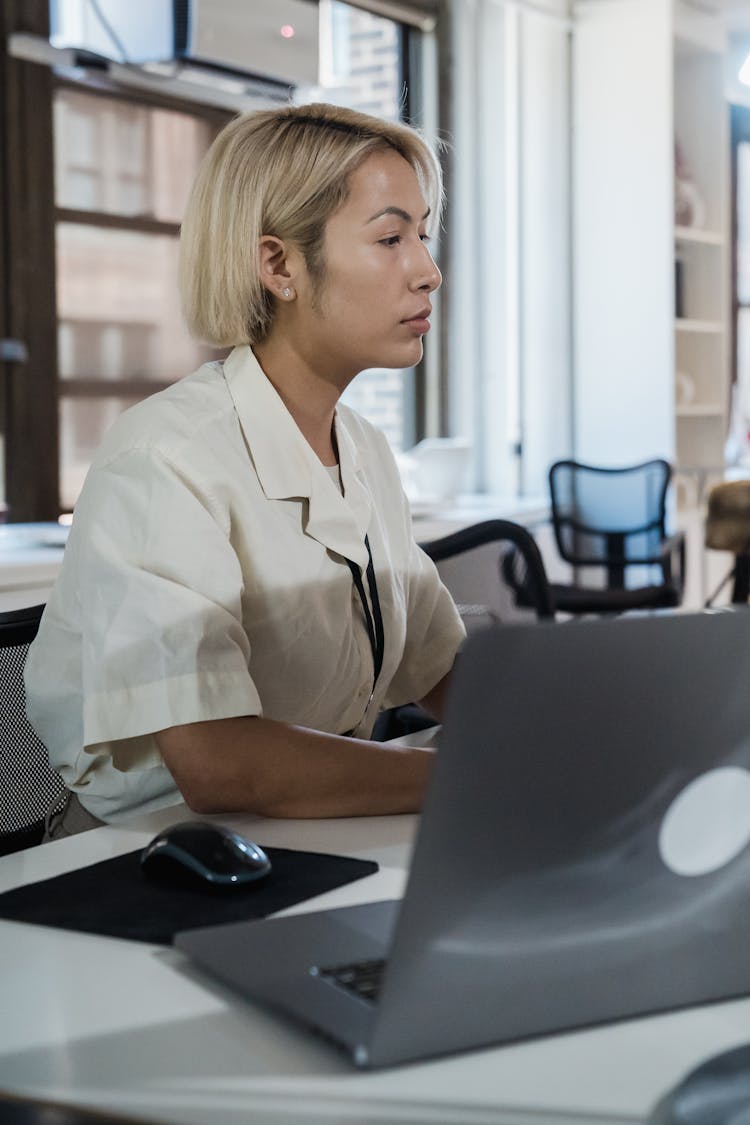 Vertical Shot Of Woman Sitting In An Office And Laptop On Desk In Foreground