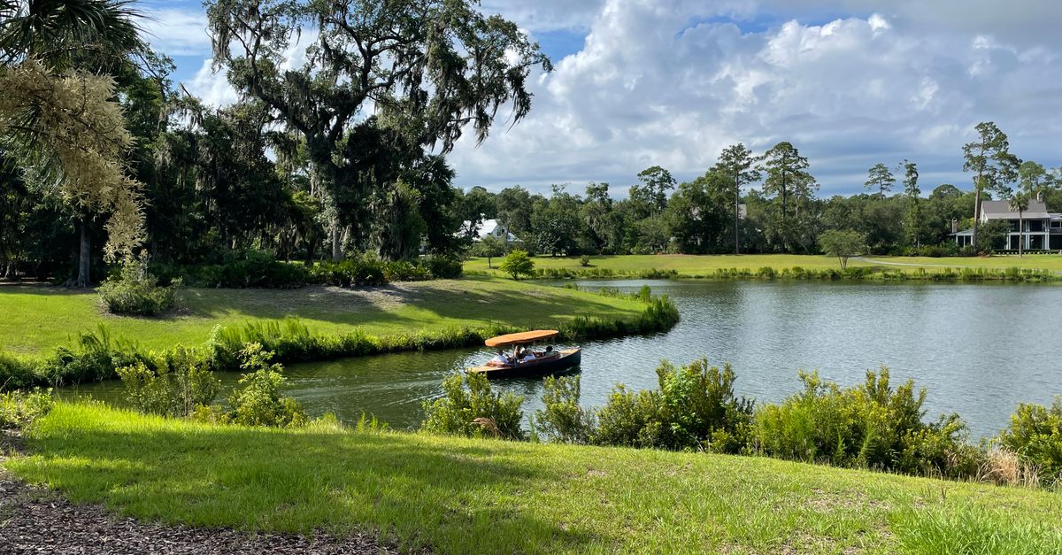 Tranquil countryside scene of a small boat on a lake surrounded by lush greenery in Bluffton, SC.