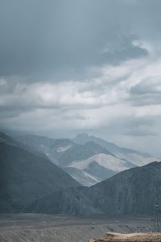 Scenic view of mountains with a dramatic cloudy sky, creating a moody atmosphere.