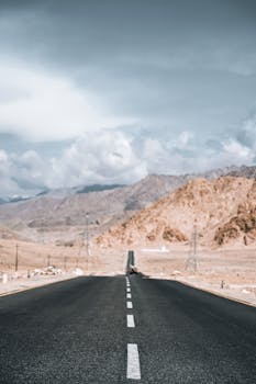 Long stretch of empty road through barren mountains, ideal for travel and adventure themes.