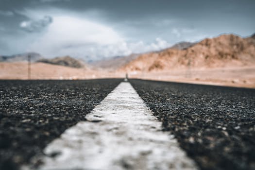 A long desert road with a central white line leading into the horizon.
