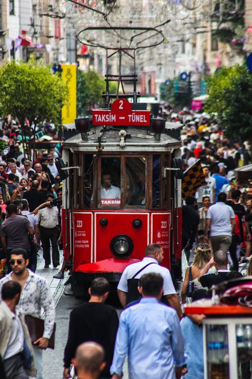 A Moving Tramway Surrounded by People Walking on the Street of a City