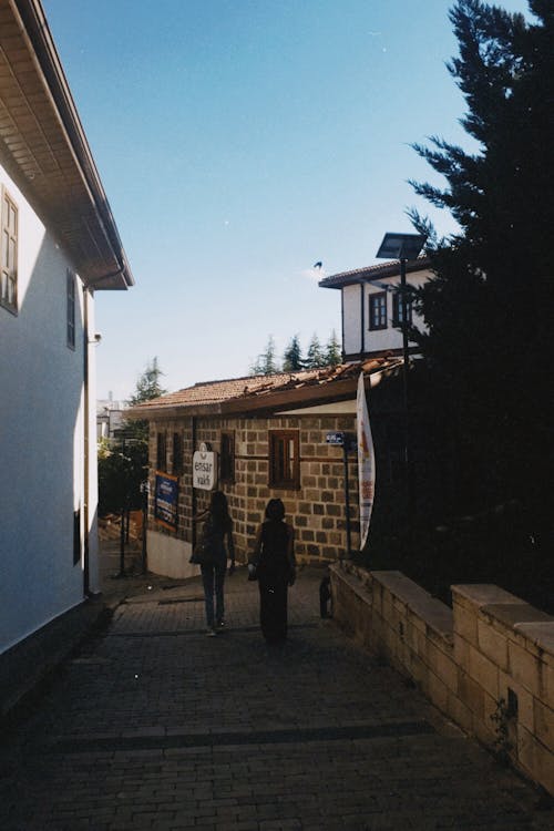 People Walking on a Narrow Cobblestone Alley