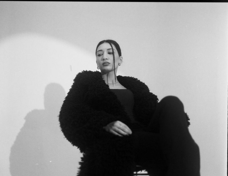 Black and white photo of woman in fur coat sitting