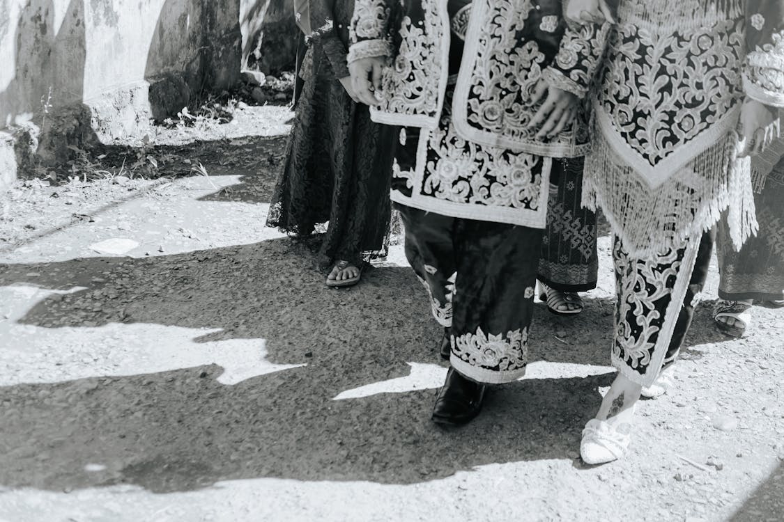 Grayscale Photography of People in Traditional Clothing Walking on the Street