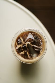 Chilled iced coffee with ice cubes in a takeaway cup from a top view perspective.