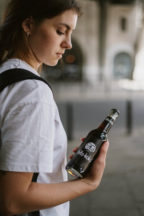 Woman in White Shirt Holding Black Bottle