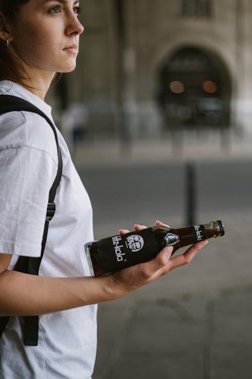 Woman in a White Shirt Holding a Soft Drink Bottle