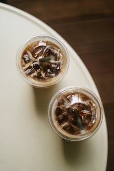 Top view of iced coffee in two disposable cups on a round table.