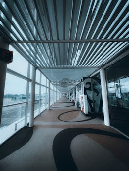 Spacious indoor airport corridor with glass windows and patterned flooring.