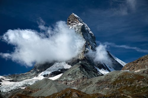 Snow Covered Mountain Surrounded by White Clouds Under Blue Sky