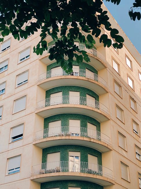 A modern urban residential building with semicircular balconies and shutters.
