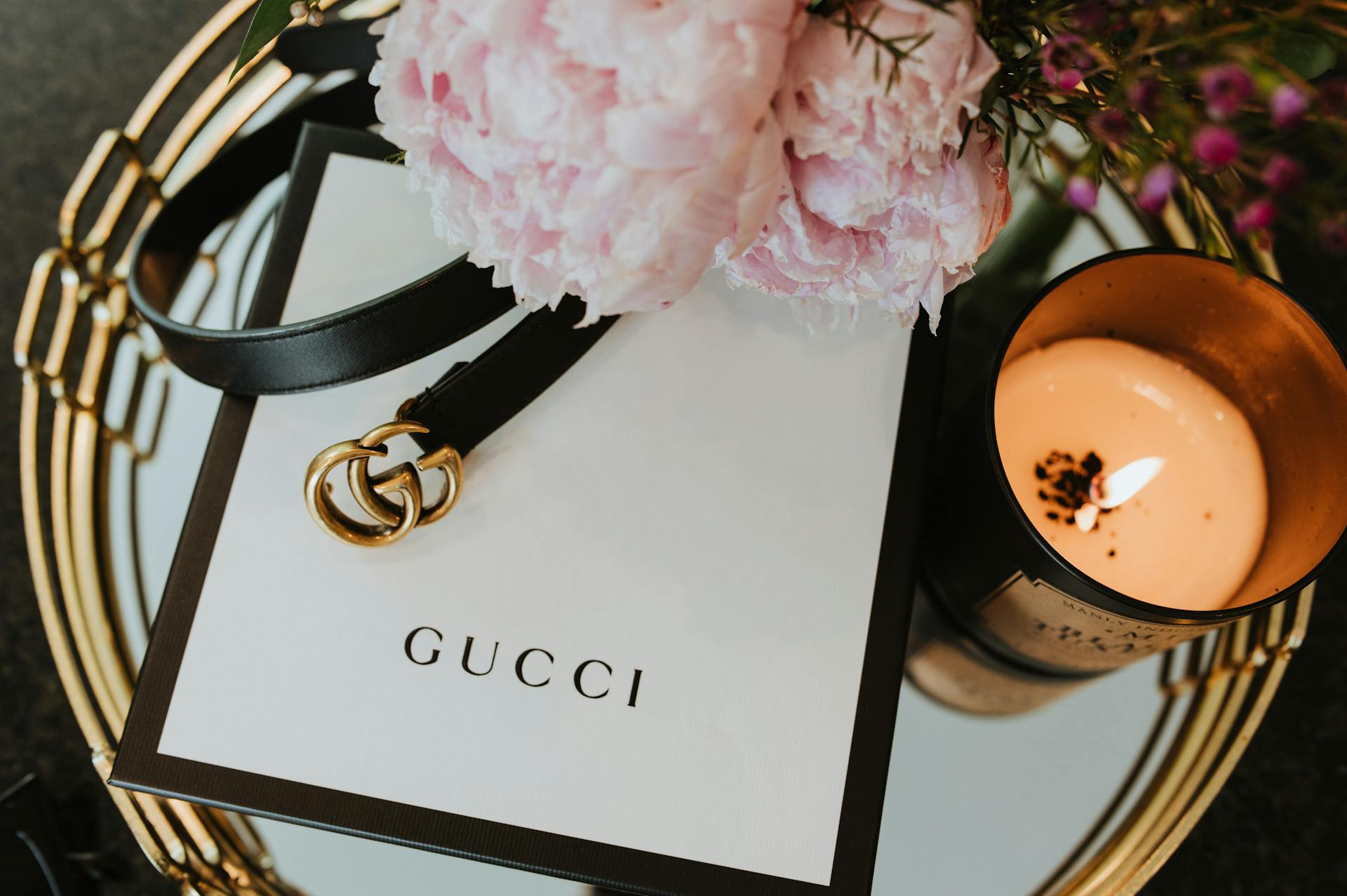 Stylish Gucci belt with candle and floral accents, showcasing luxury fashion aesthetics.