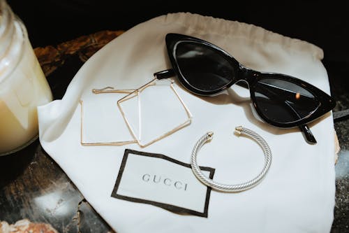 Free Black Framed Sunglasses and Jewelries on a Gucci Dust Bag Stock Photo