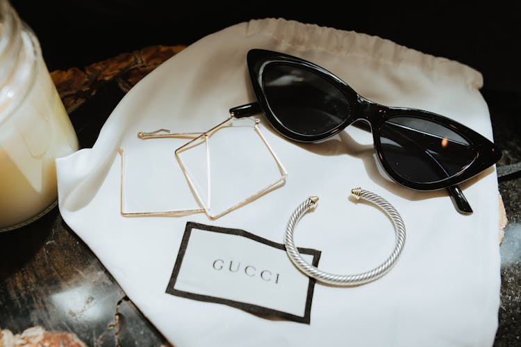 Black Framed Sunglasses And Jewelries On A Gucci Dust Bag