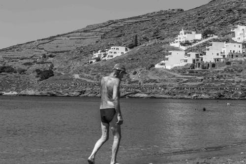 Shirtless Man Walking on Shore