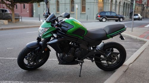 Free A vibrant green Kawasaki motorcycle parked on a city street beside historic buildings. Stock Photo