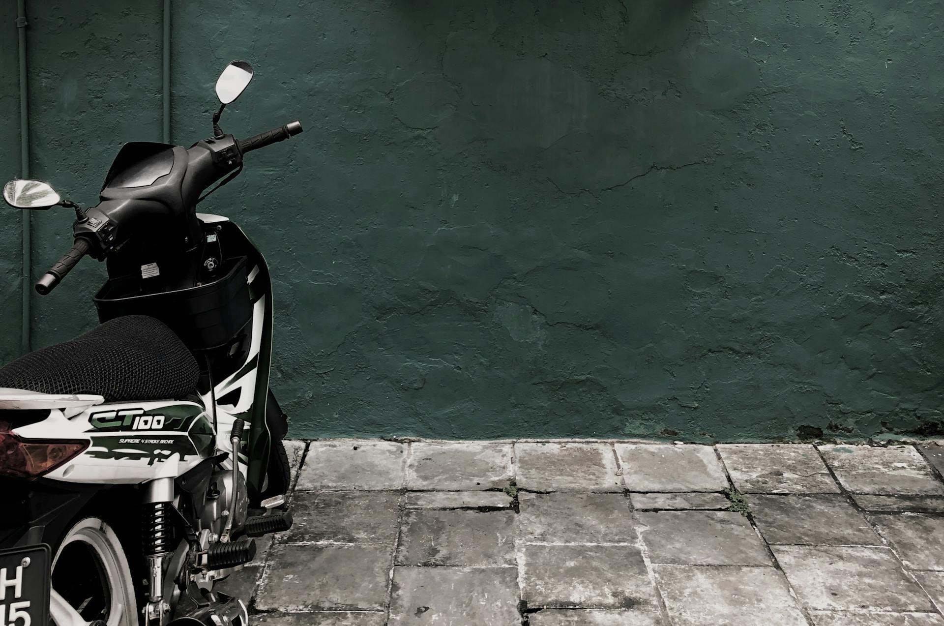 Black and White Ct 100 Motorcycle Parked Near Concrete Wall