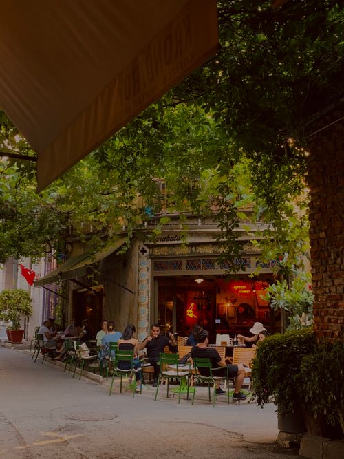 Free Charming street café with people dining amid lush greenery and urban vibes. Stock Photo