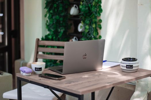 A cozy café workspace featuring a laptop, coffee cup, and smartphone on a wooden table, ideal for remote work.