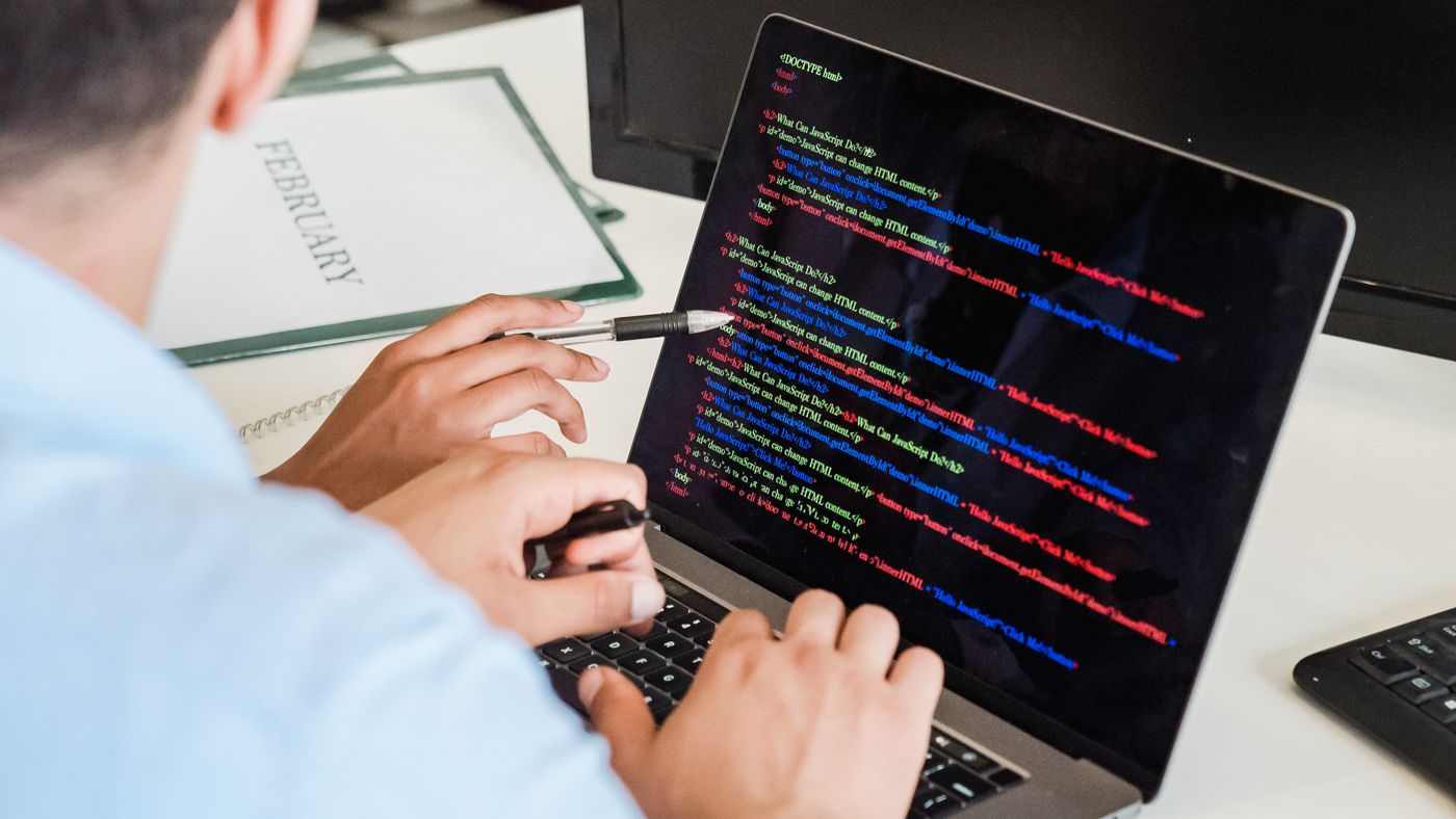 On a managed network, the fix often belongs to the proxy, not the editor. Photo: Mizuno K / Pexels; illustrative. Person pointing at colorful code on a laptop screen while typing