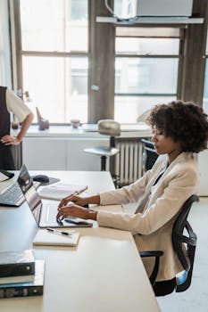 Woman typing on laptop in a bright, modern office setting.