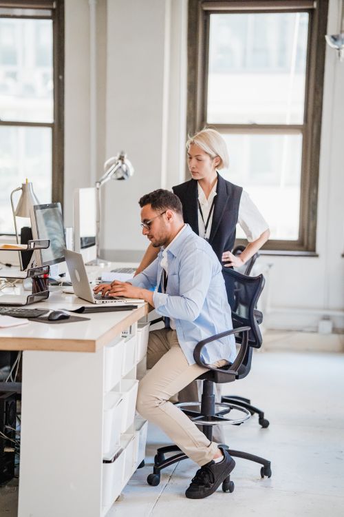 Free Two business professionals engaged in work at a modern office, using a laptop. Stock Photo
