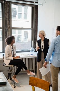 Three colleagues engage in a casual meeting in a modern office space, collaborating on a project.