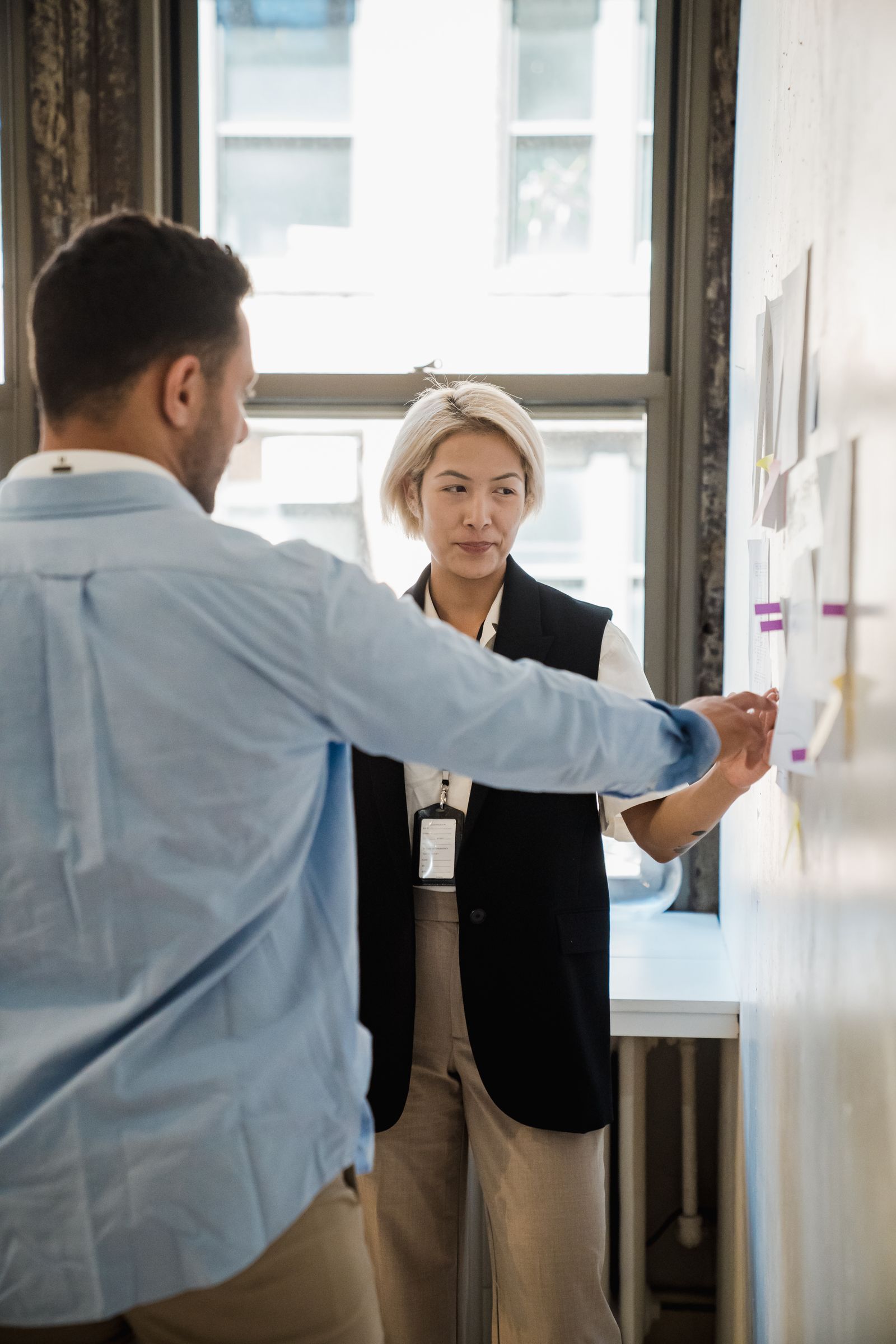 Professionals discussing plans beside a wall of sticky notes.