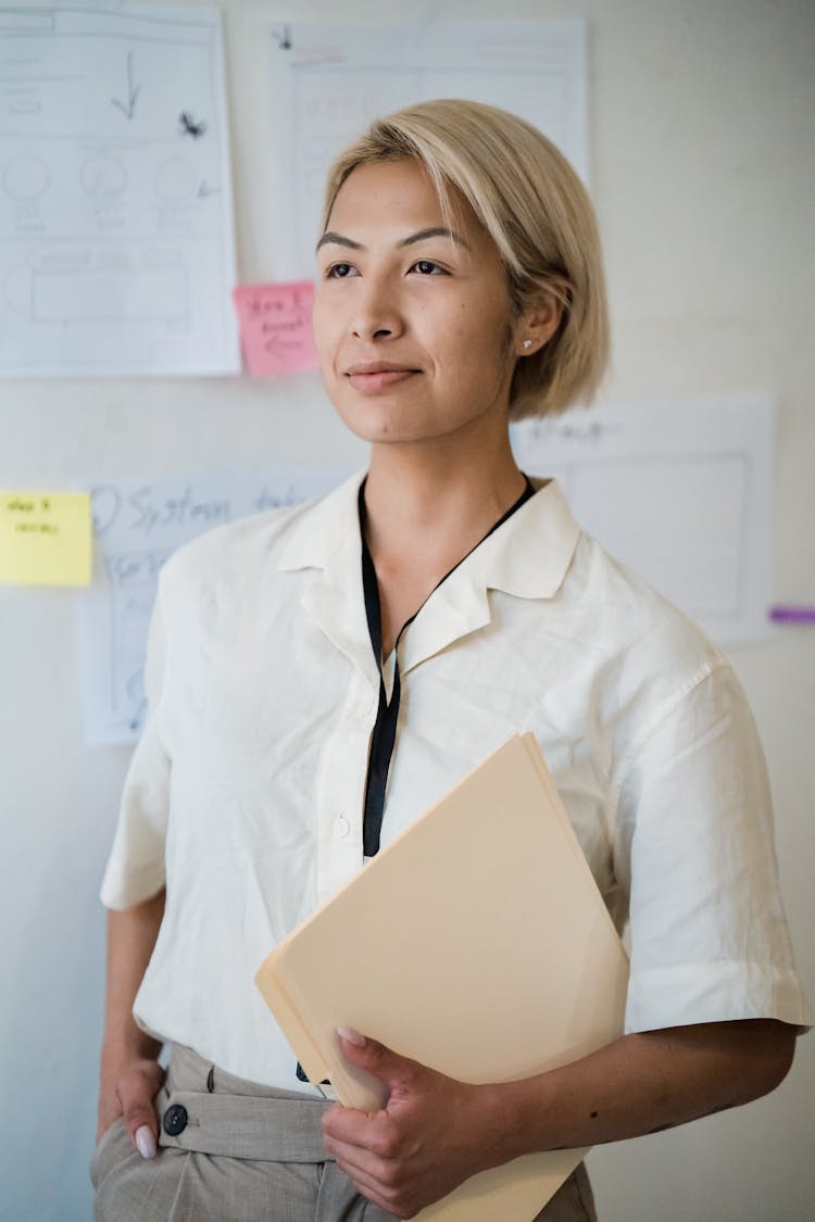 Office Worker Standing And Holding A Folder With A Hand In The Pocket 