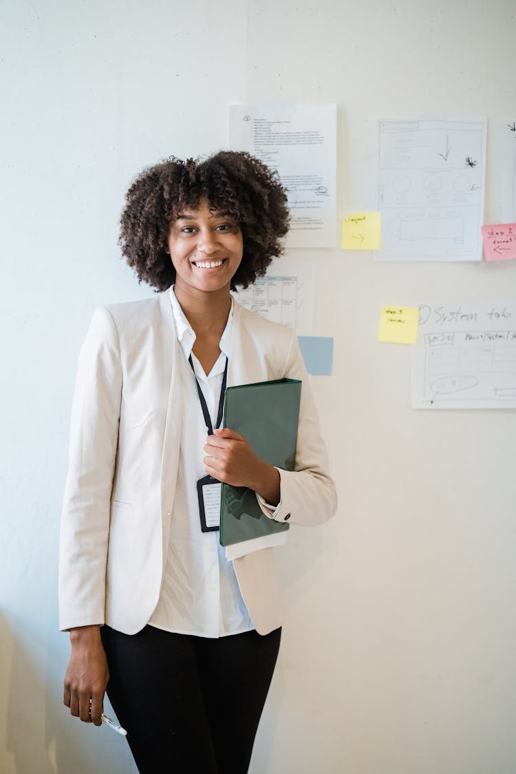 Businesswoman Standing In An Office And Holding A Folder And A Pen 